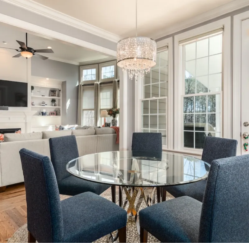 Elegant dining room with glass table and crystal chandelier.