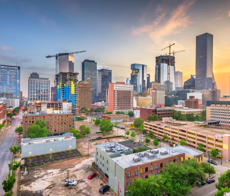 City skyline at twilight with construction cranes.