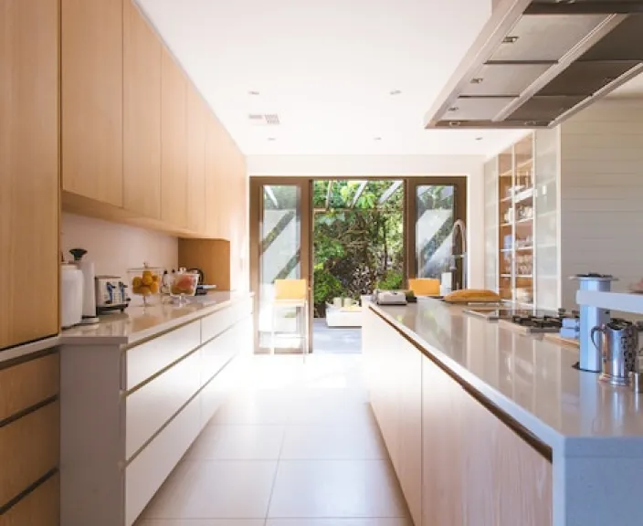 Modern kitchen interior with natural light and wooden cabinets.