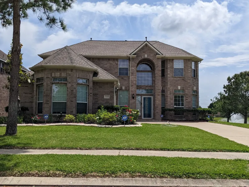 Two-story suburban brick house with green lawn