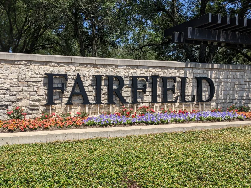 Fairfield sign with flowers and stone wall.