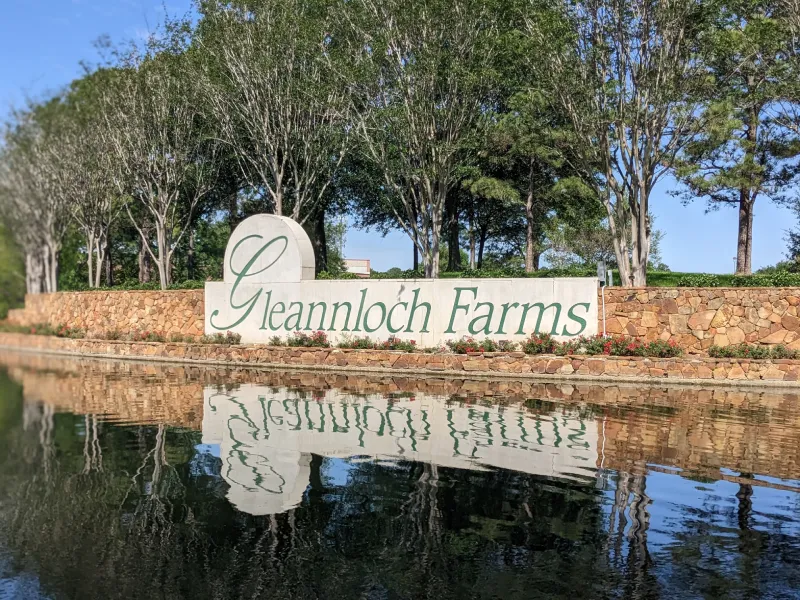Gleannloch Farms sign reflecting on water with trees.