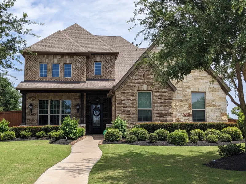 Suburban brick house with landscaped front yard.