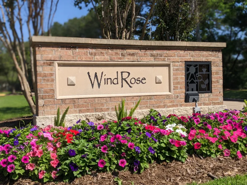WindRose sign with colorful flowers in sunlight.