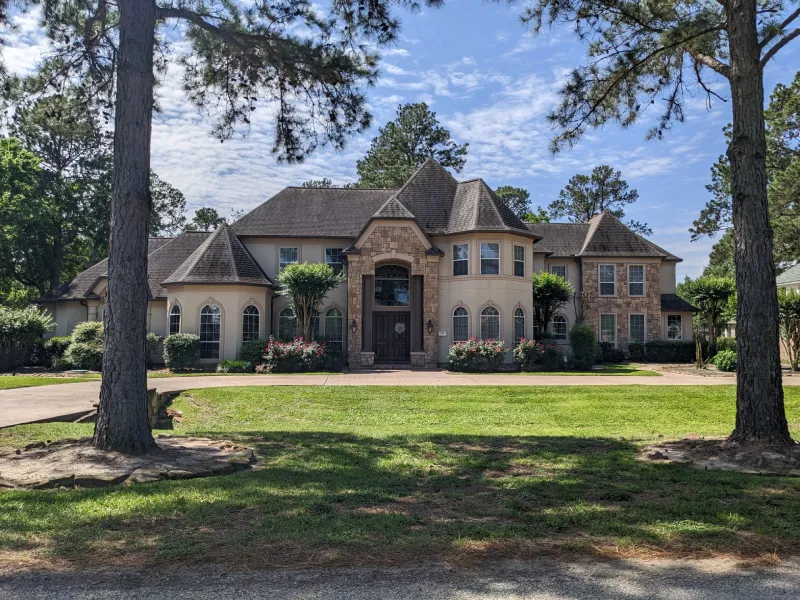 Elegant suburban house with landscaped yard and trees.