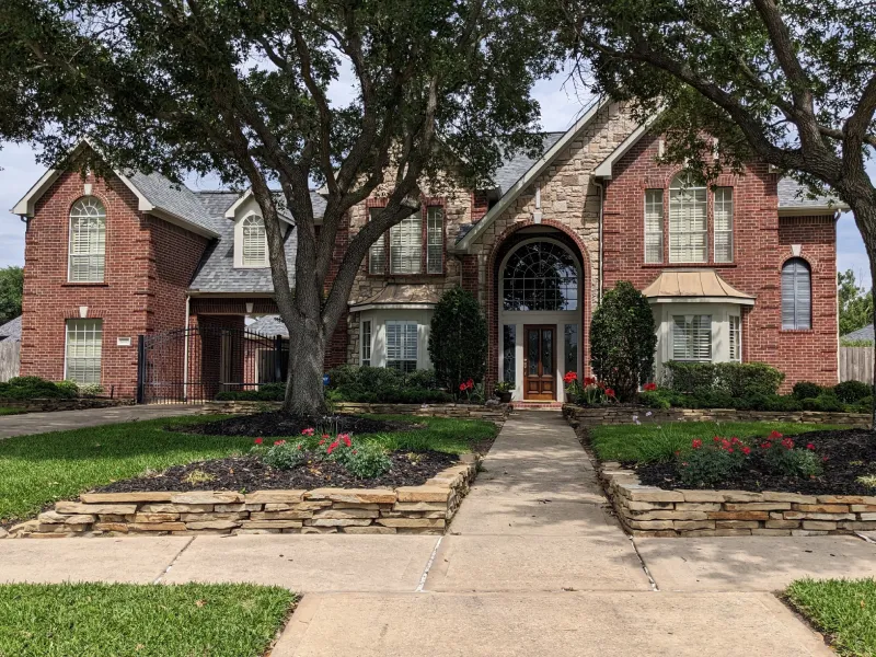 Brick two-story house with landscaped front yard.